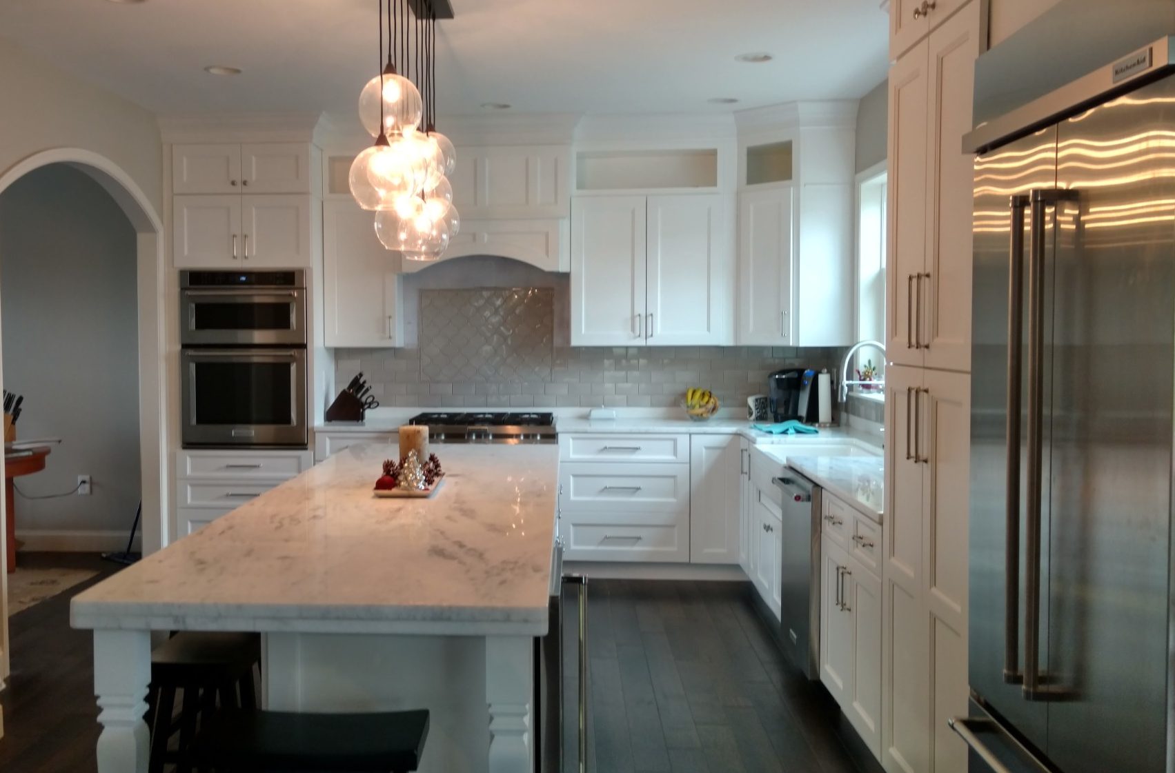 Bright modern kitchen with white cabinetry, marble island, and stainless steel appliances.